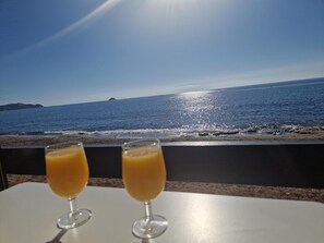 Two glasses of orange juice on a table with a view of the sea and a distant island. - Comfortable apartment with golf course view - 4 guests (San Juan de los Terreros)