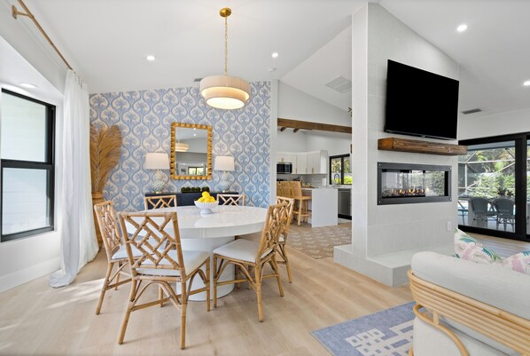 A modern kitchen with white cabinets, a built-in oven, and a large window overlooking a garden.