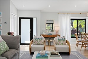 A modern living room with a sofa set, a coffee table with books, a side table, and a dining area with chairs.