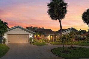 A residential house with a garage, a well-maintained lawn, and a driveway leading to the entrance.
