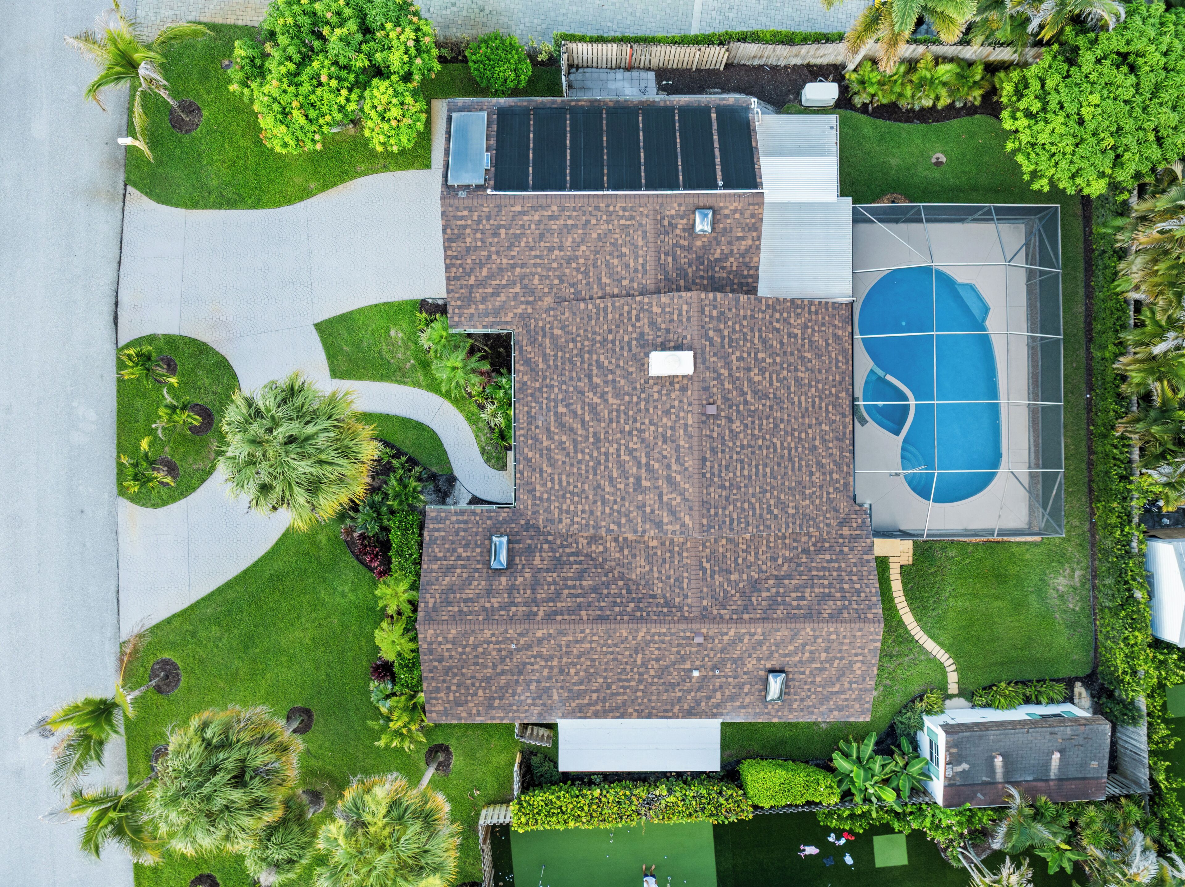 A residential property with a basketball court, solar panels, and a well-maintained lawn.