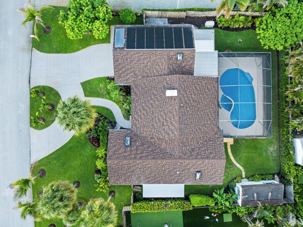 A residential property with a basketball court, solar panels, and a well-maintained lawn.