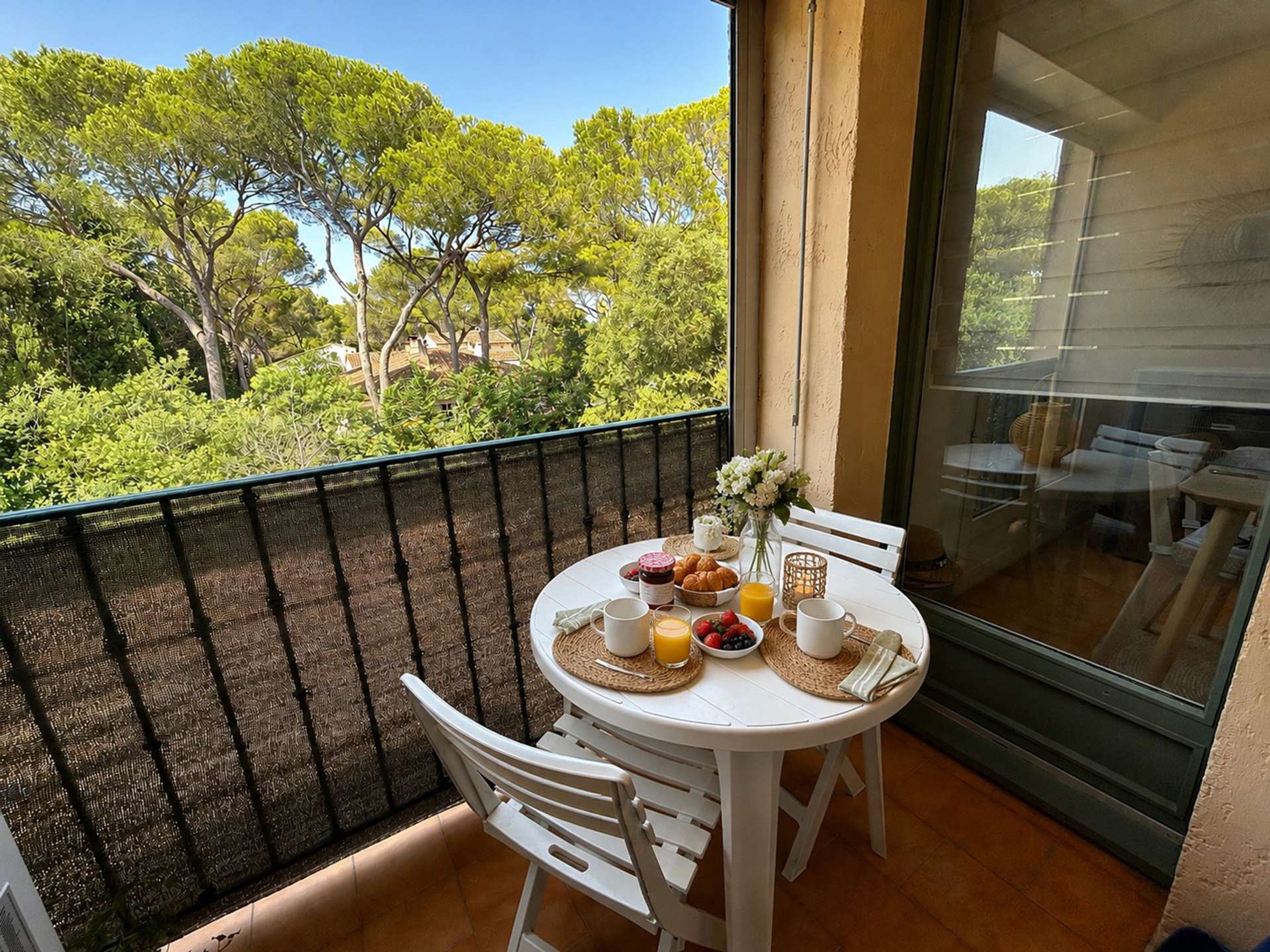 A balcony with a table set for breakfast, overlooking a lush green landscape.