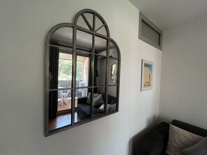 A room with a large arched window, a framed picture on the wall, and a black sofa. - Studio cabin near beach - 4 guests (Saint-Aygulf)