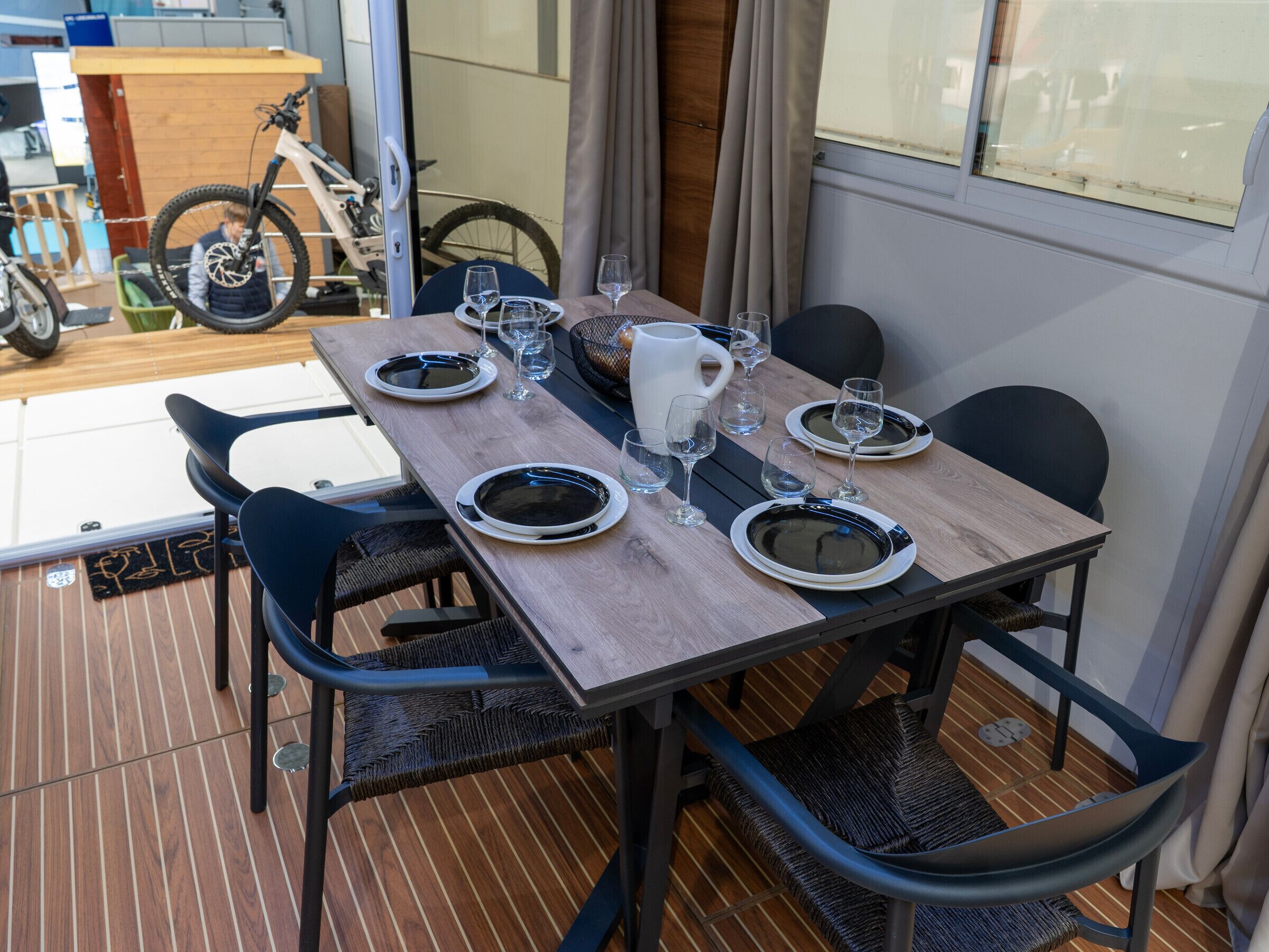 A dining table set with plates, glasses, and a pitcher, surrounded by chairs.