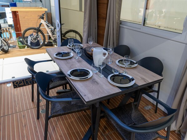 A dining table set with plates, glasses, and a pitcher, surrounded by chairs.