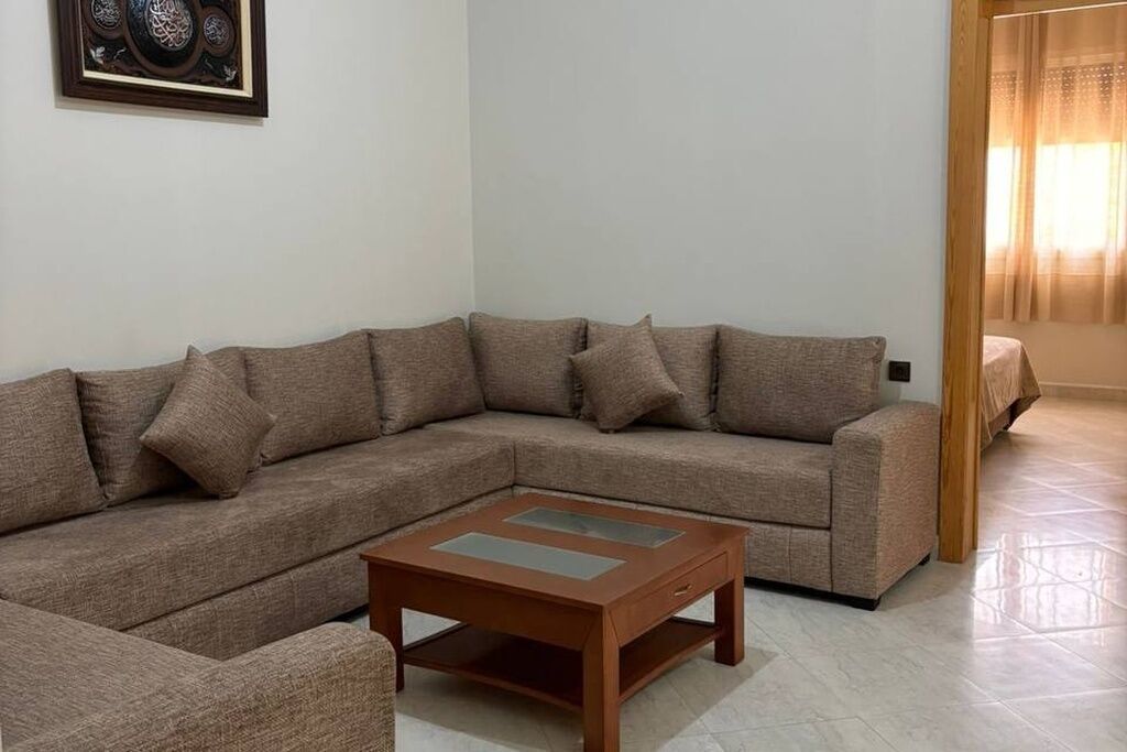 A living room with a sectional sofa, a wooden coffee table, and a framed artwork on the wall.