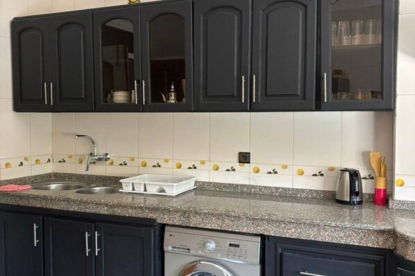 A kitchen with dark cabinets, a granite countertop, a built-in dishwasher, and a sink.