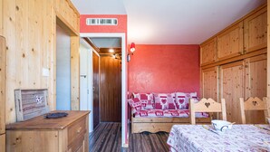 Quarto de madeira com uma cama, cômoda de madeira e parede vermelha.