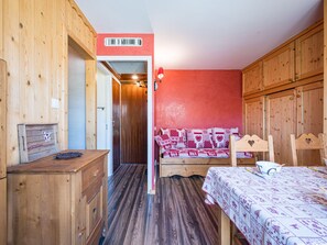 Ein Zimmer mit Holzboden, einem Bett, einer Holzkommode und einer roten Wand.