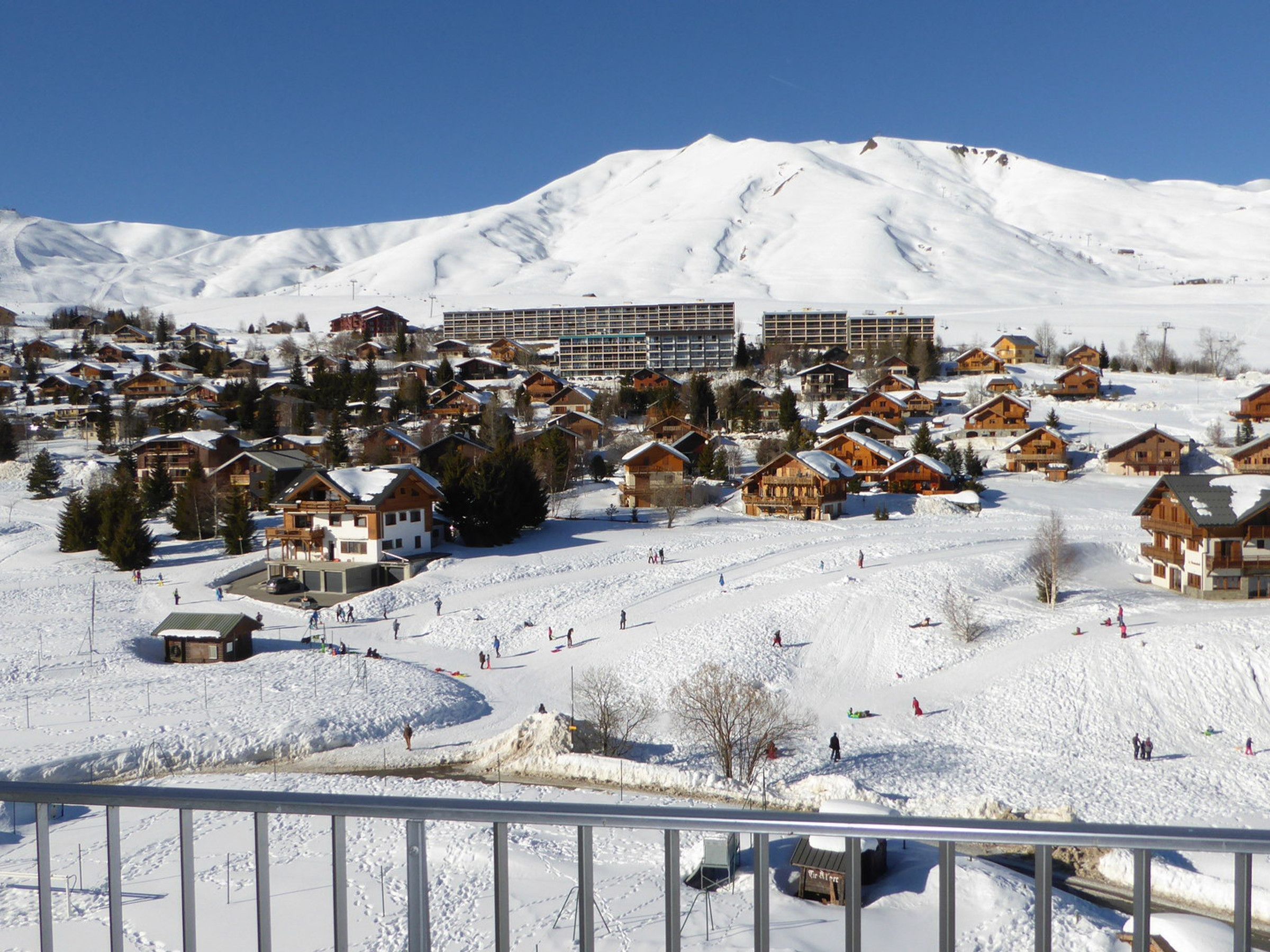 Estância de esqui coberta de neve com chalés de madeira e um grande edifício de hotel.