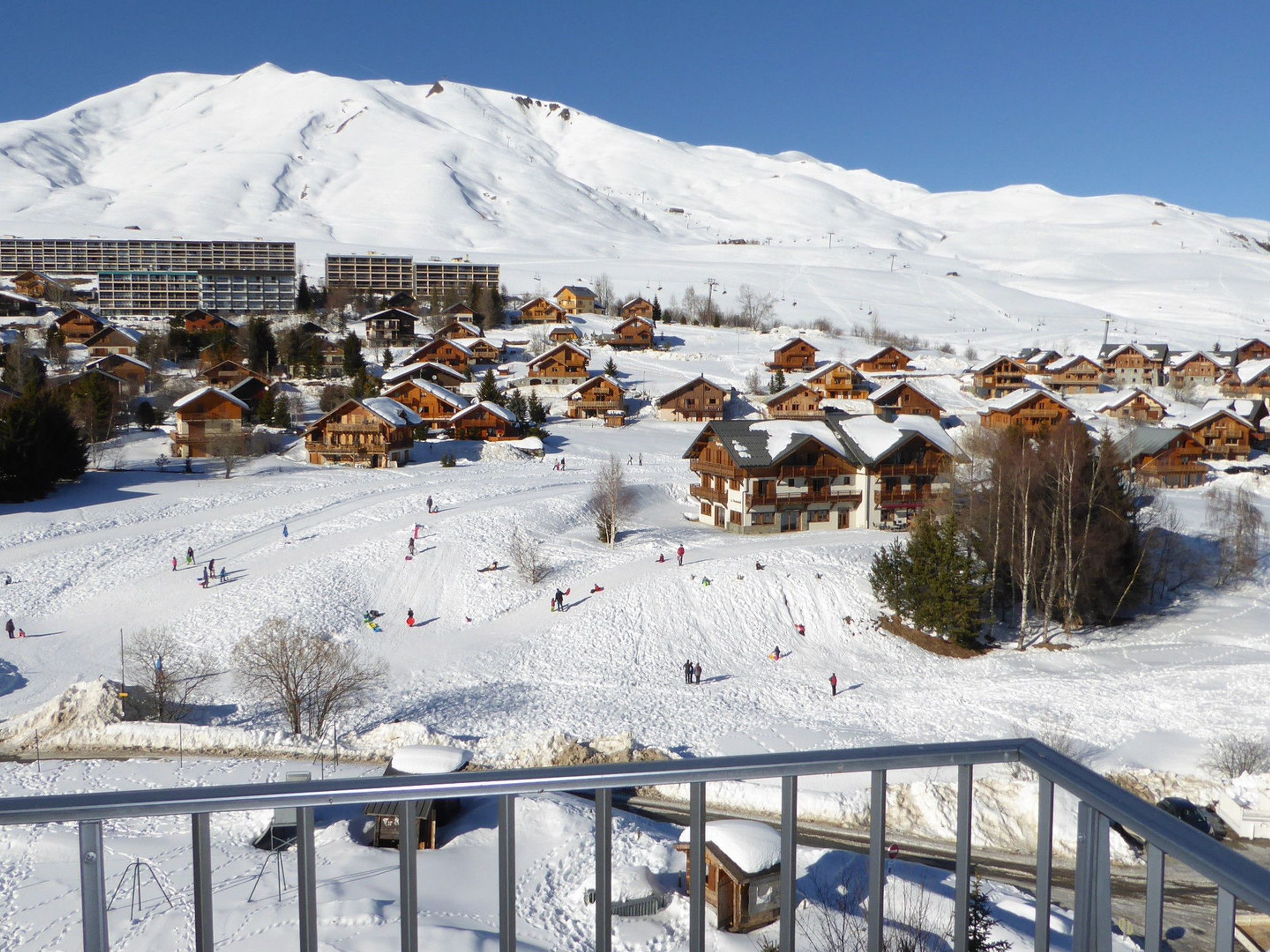 Une station de ski enneigée, avec des chalets en bois et un télésiège en arrière-plan.