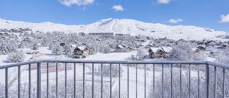 Une ville de montagne enneigée, avec des maisons traditionnelles en bois et un grand bâtiment en arrière-plan.