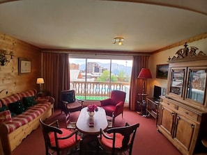 A cozy living room with a sofa, chairs, a table with flowers, a TV, and a cabinet. - Spacious apartment - 8 guests, central location (Huez)