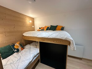 Ein Stockbett mit einem Holzkopfende und einem unterem Bett mit einer weißen Matratze.