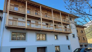 A multi-story building with balconies, large windows, and a car parked in front. - Pleasant apartment, west balcony - 6 guests (Lanslevillard)