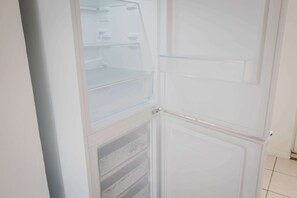 A white interior with a refrigerator and a microwave. - Modern 3 Bedroom House With WiFi (Northampton)