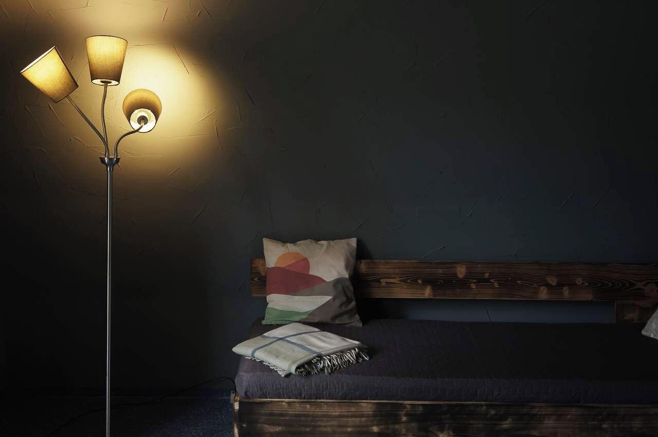 Quarto com cama, luminária de chão e parede com textura.