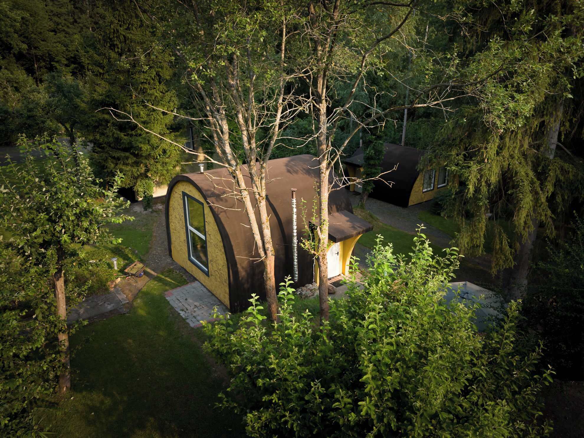 Una casa de techo curvo rodeada de un bosque frondoso.