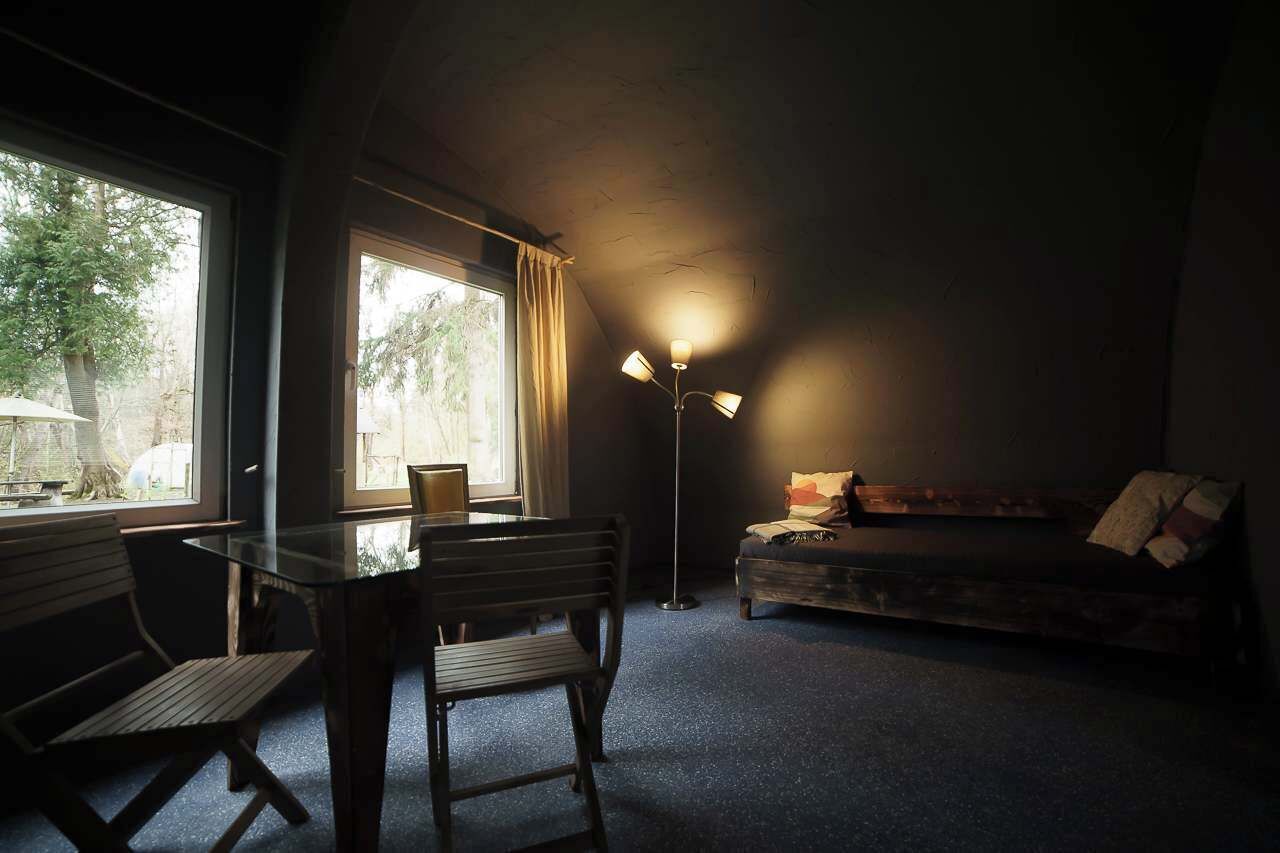 Um quarto com uma cama, uma mesa com cadeiras e um abajur.