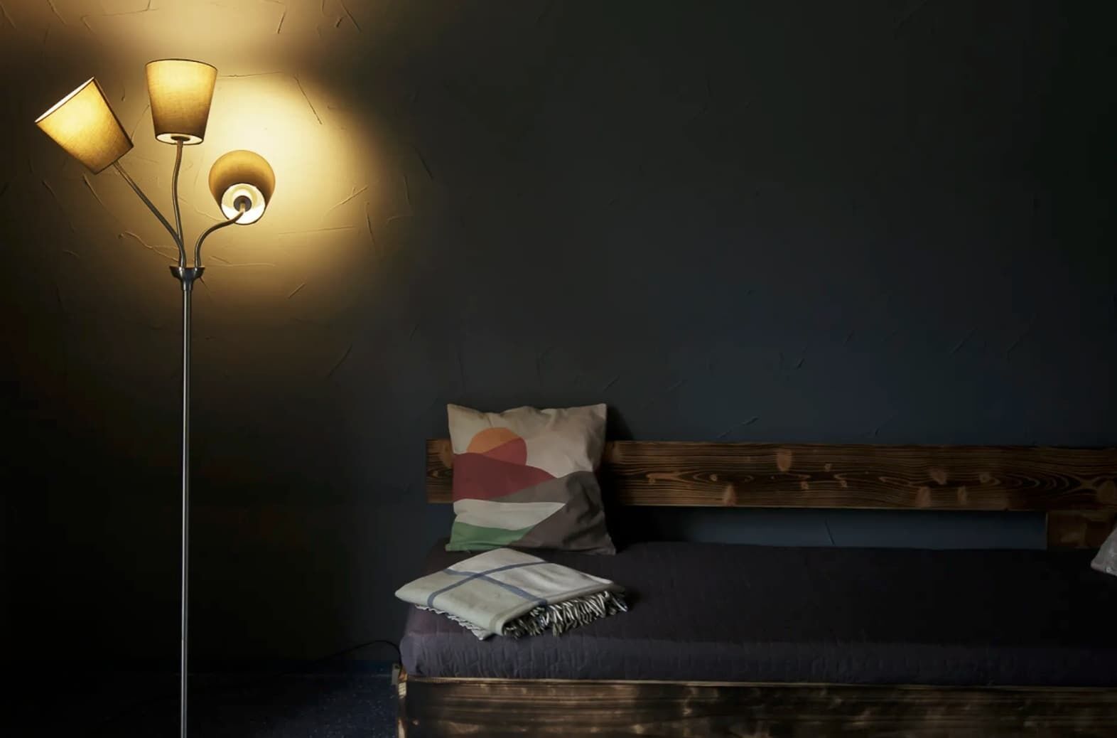 Una habitació amb un llit, una làmpada de peu i una paret amb un relleu decoratiu.