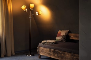 A room with a bed, a floor lamp, and a curtain.