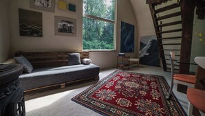 A cozy room with a loft bed, a sofa, a rug, and artwork on the walls. - Point NEMO Digital Detox - Maga Capsule with Sauna (Mirsk)