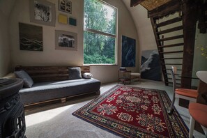 A cozy room with a loft bed, a sofa, a rug, and artwork on the walls. - Point NEMO Digital Detox - Maga Capsule with Sauna (Mirsk)
