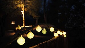 A string of lights on a wooden fence in a dark outdoor setting. - Point NEMO Digital Detox - Maga Capsule with Sauna (Mirsk)