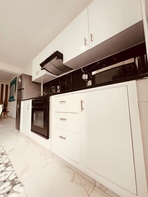 A modern kitchen with white cabinetry, a black stove, and a stainless steel refrigerator. - Peaceful 1-bedroom apartment with AC and fully equiped in Santa Maria (Santa Maria)