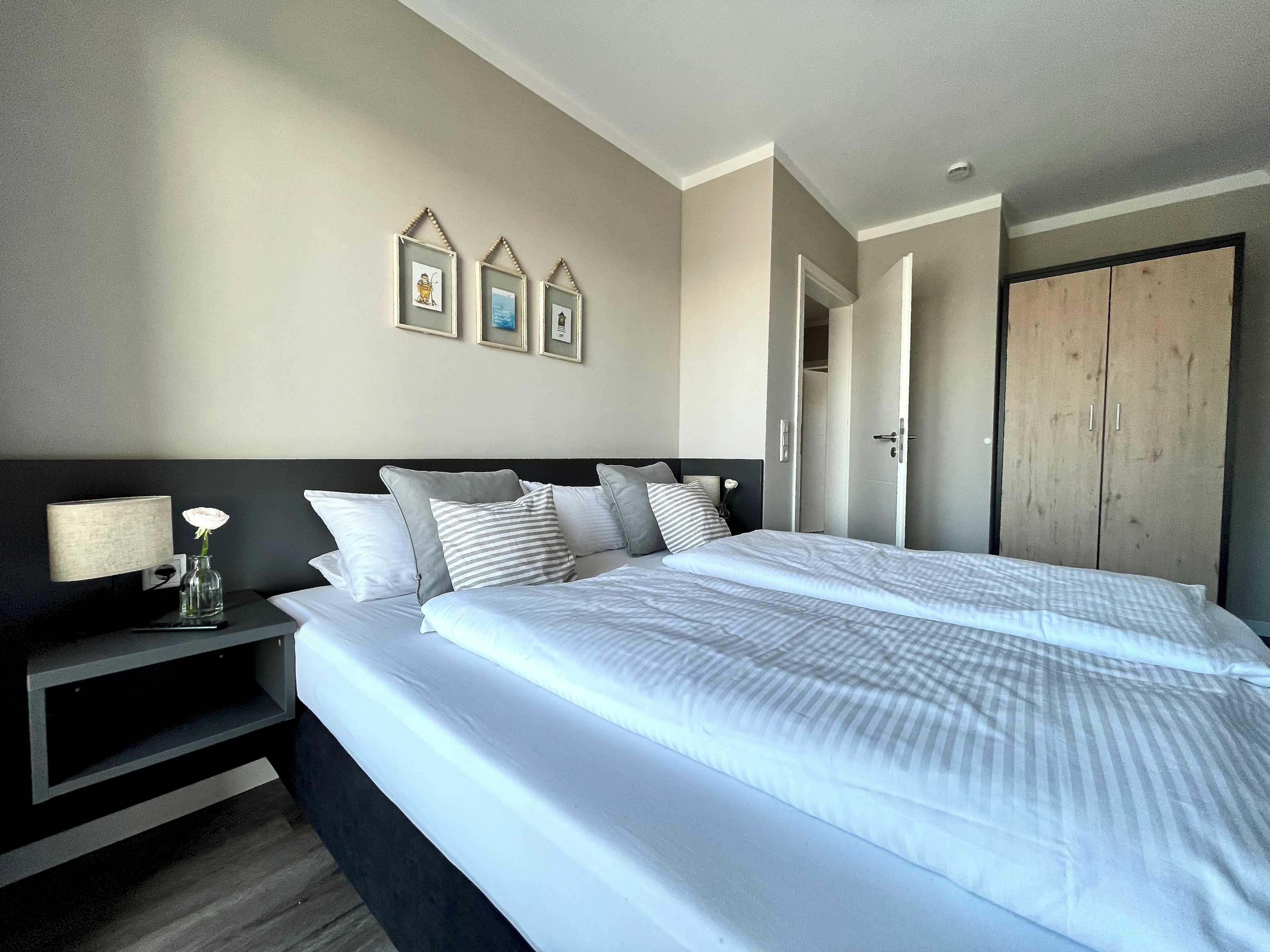 A modern bedroom with a large bed, bedside table, and a wardrobe.