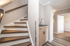 A staircase with wooden steps and a vase on a cabinet. - Vacation Home in Büsum, 124 m², Sauna, Fireplace, Parking Space (Büsum)