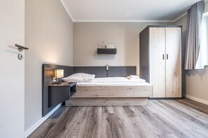 Ein modernes Schlafzimmer mit Bett, Nachttisch, Lampe und einem Kleiderschrank.