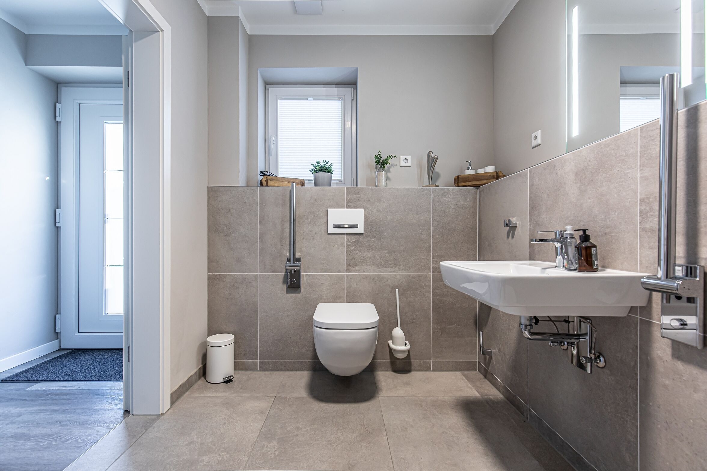 Een moderne badkamer met toilet, hygiëneschuimer en wastafel.