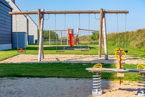 A playground with swings, a slide, and a seesaw. - Vacation Home in Büsum, 124 m², Sauna, Fireplace, Parking Space (Büsum)