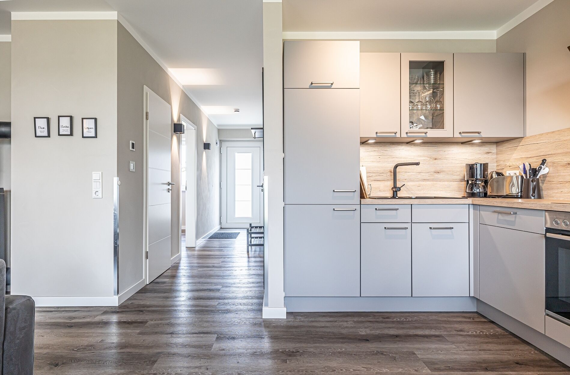 A modern kitchen with white cabinetry, a wooden countertop, and a built-in oven.