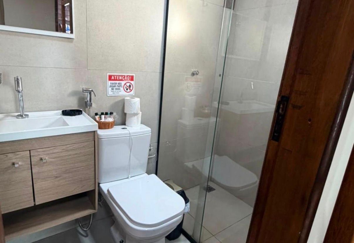 A bathroom with a toilet, sink, and shower area.