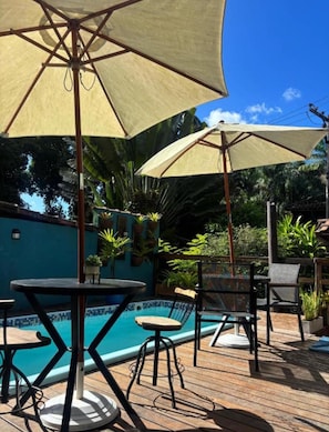 A poolside area with a pool, outdoor furniture, and umbrellas. - Recanto das Jaqueiras (Angra dos Reis)
