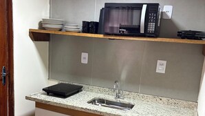Een kleine keuken met een magnetron, een spoelbak en een aanrecht.