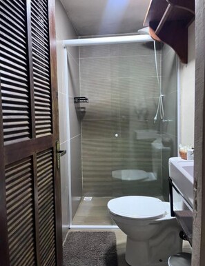A compact bathroom with a shower enclosure, a toilet, and a sink. - Recanto das Jaqueiras (Angra dos Reis)