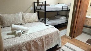 Een slaapkamer met een stapelbed, een enkel bed en een houten bank.