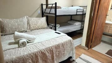 Un dormitorio con una cama litera, una cama individual y un banco de madera.
