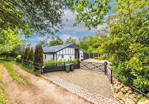 A traditional black and white house with a gravel driveway and a metal gate.
