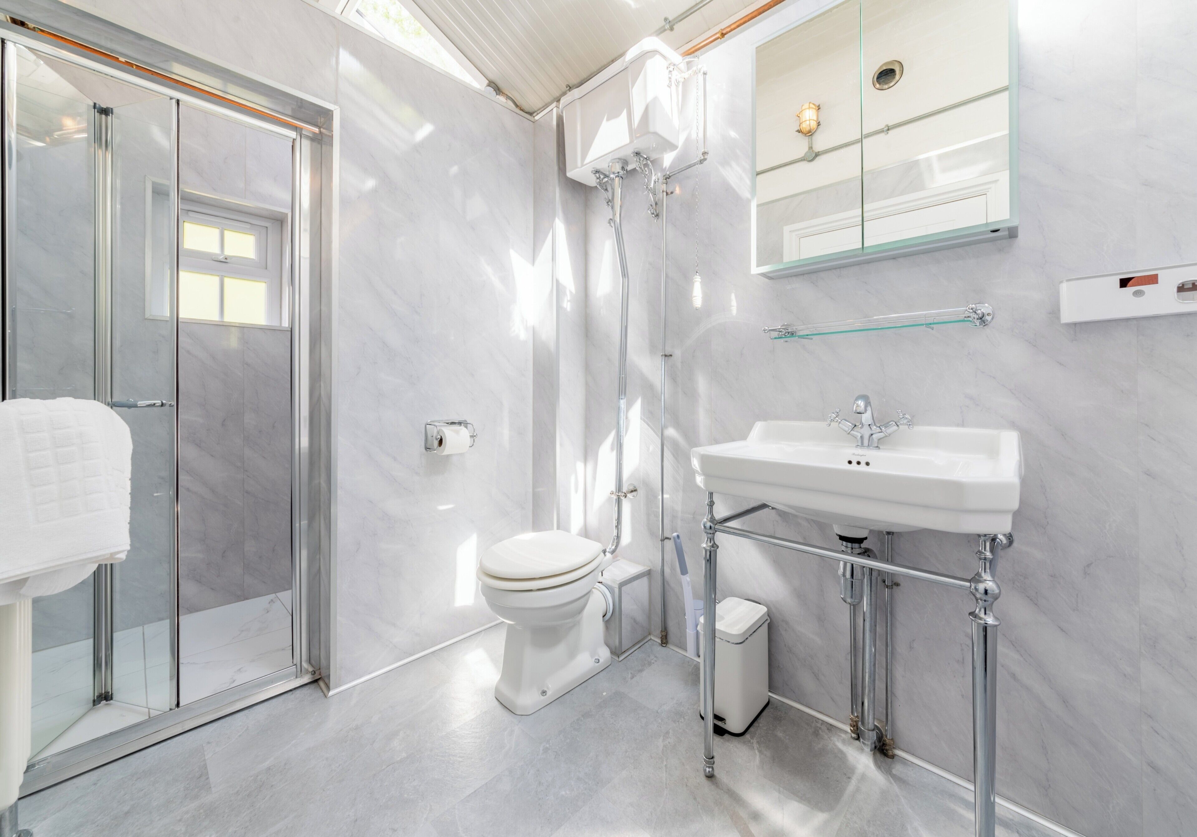 Ein modernes Badezimmer mit Duschkabine aus Glas, einer weißen Toilette und einem Standwaschbecken.