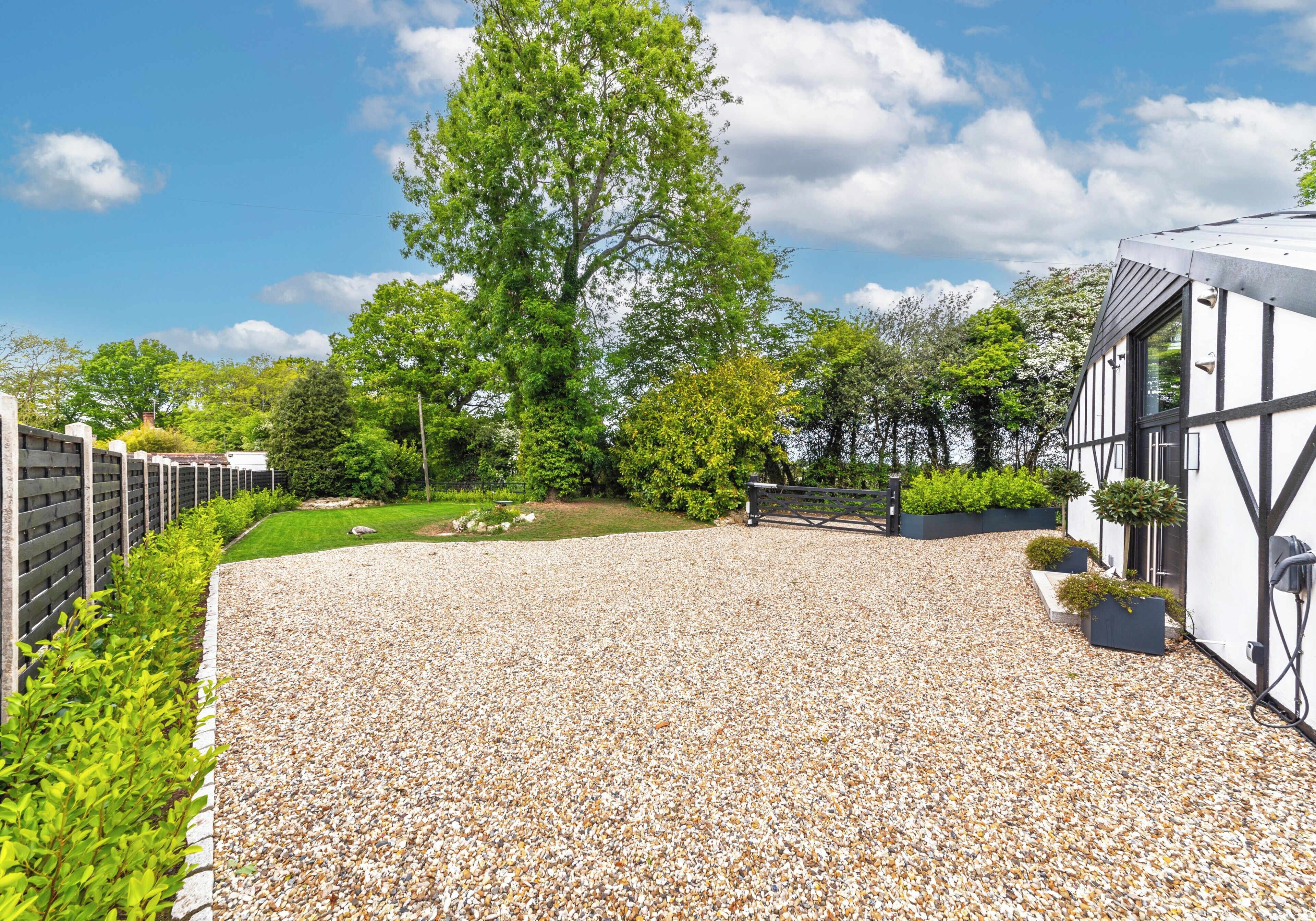 A gravel driveway leading to a building with a white exterior and black timber framing.