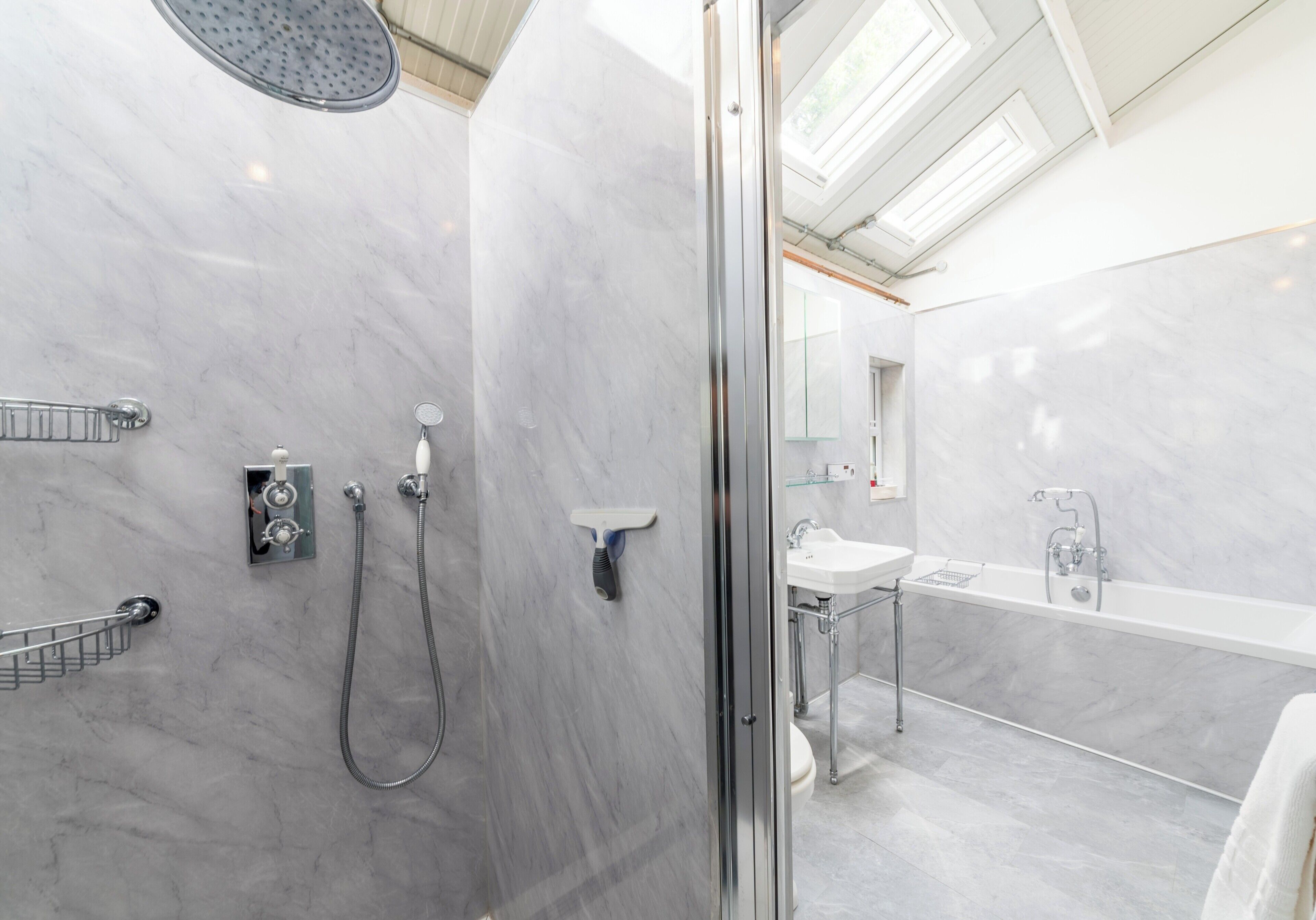 A modern bathroom with a shower, toilet, and sink, all with chrome fixtures.