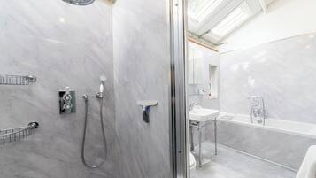 A modern bathroom with a shower, toilet, and sink, all with chrome fixtures.
