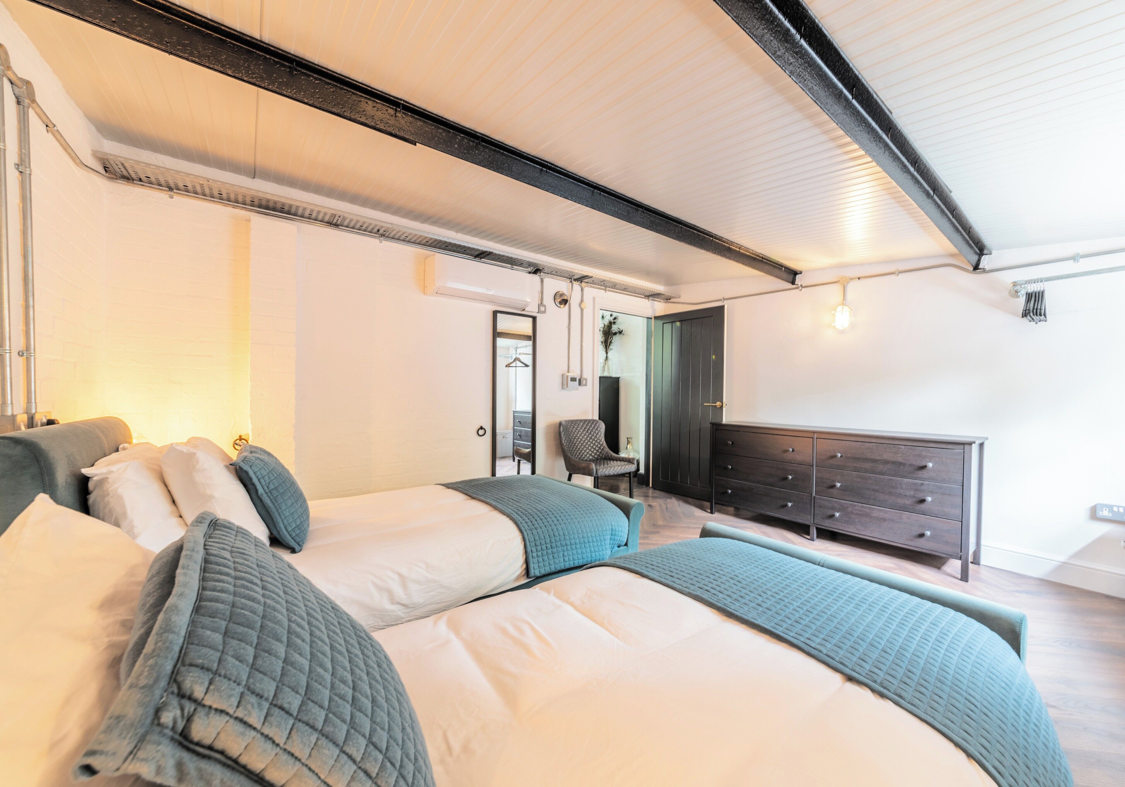 A modern bedroom with a large bed, a dresser, and a chair.