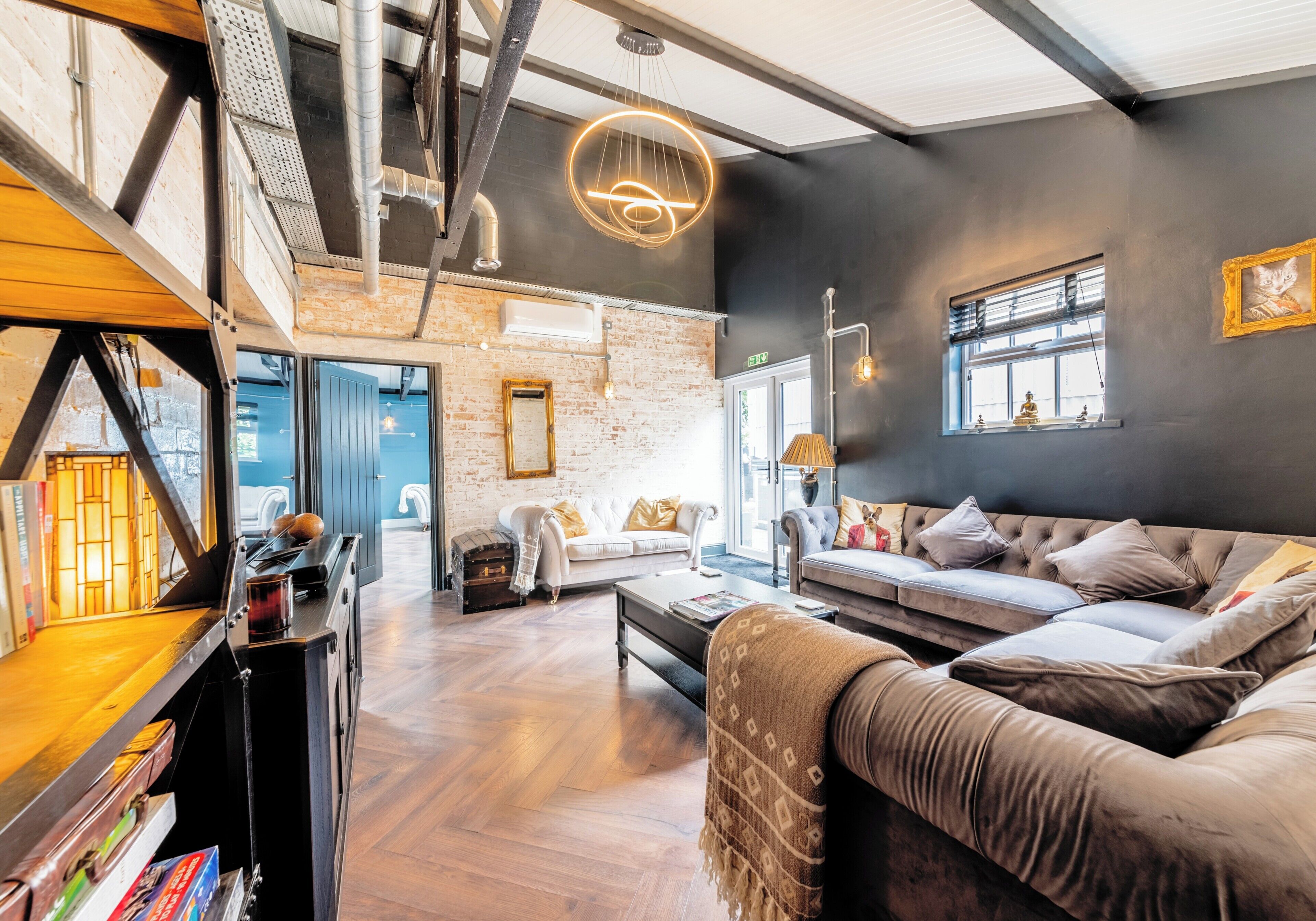 A modern interior with a loft-style ceiling, a sofa set, a fireplace, and a bookshelf.