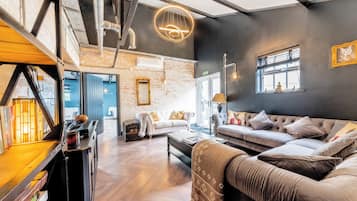 A modern interior with a loft-style ceiling, a sofa set, a fireplace, and a bookshelf.
